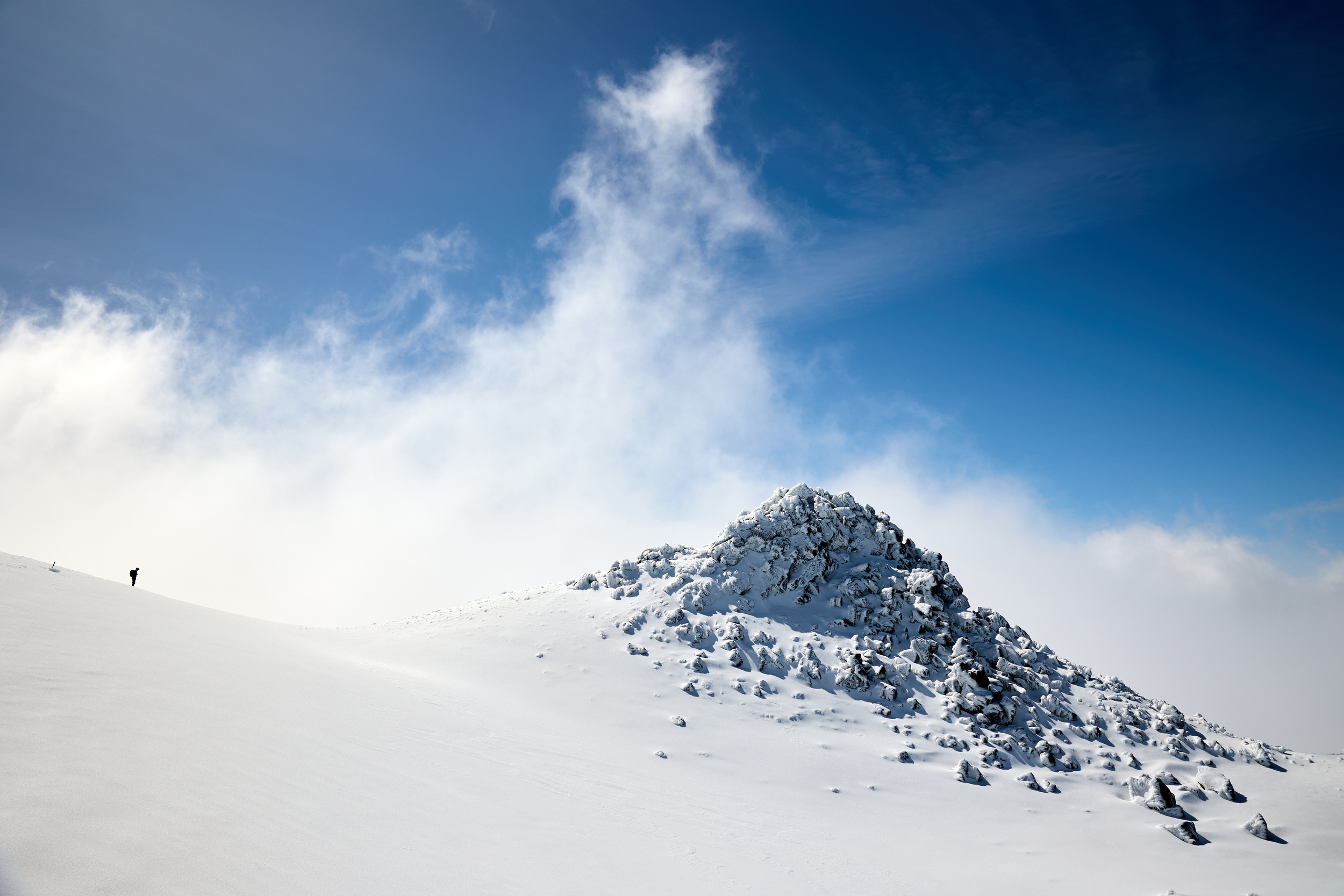 A person walking through the snowfield looking across at Fantams peak