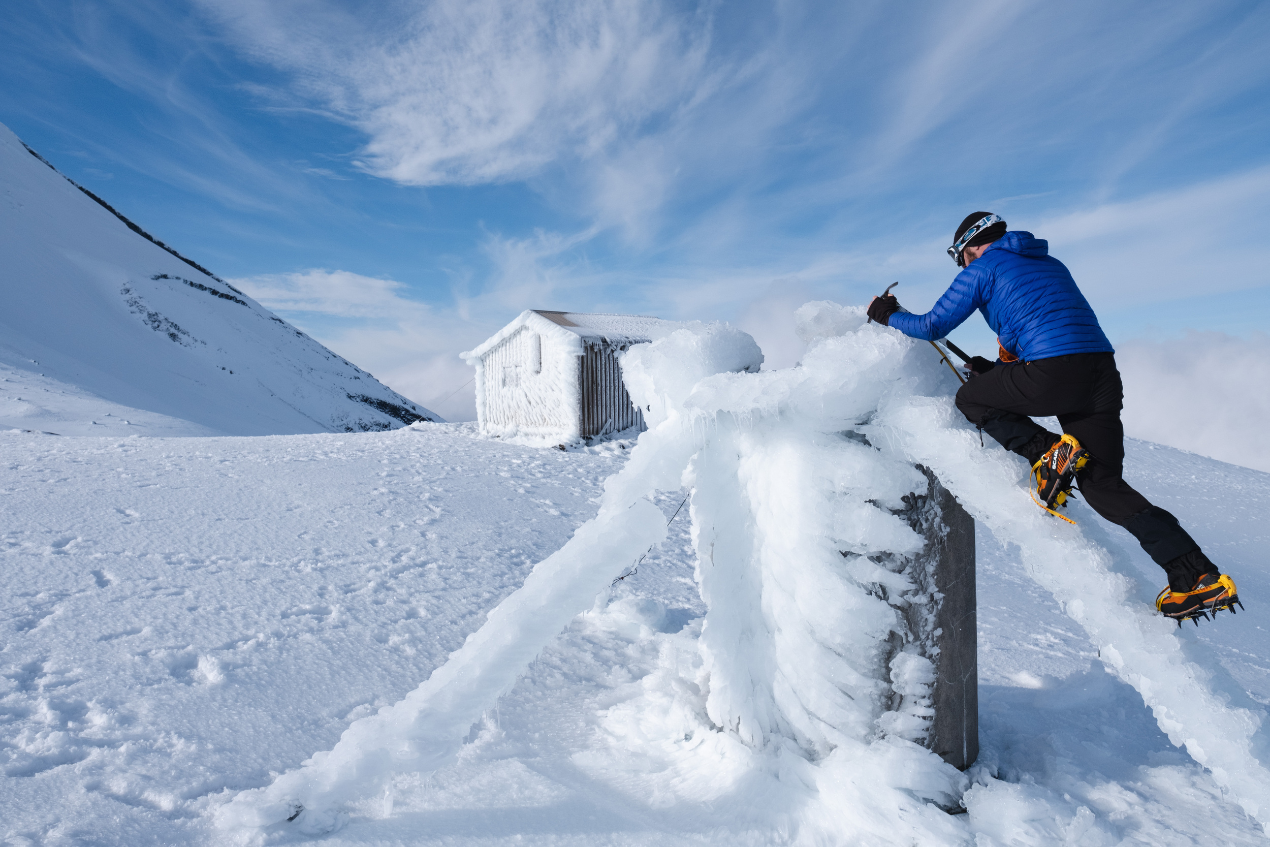 Climbing the ice-covered support cable for Syme hut's long drop toilet