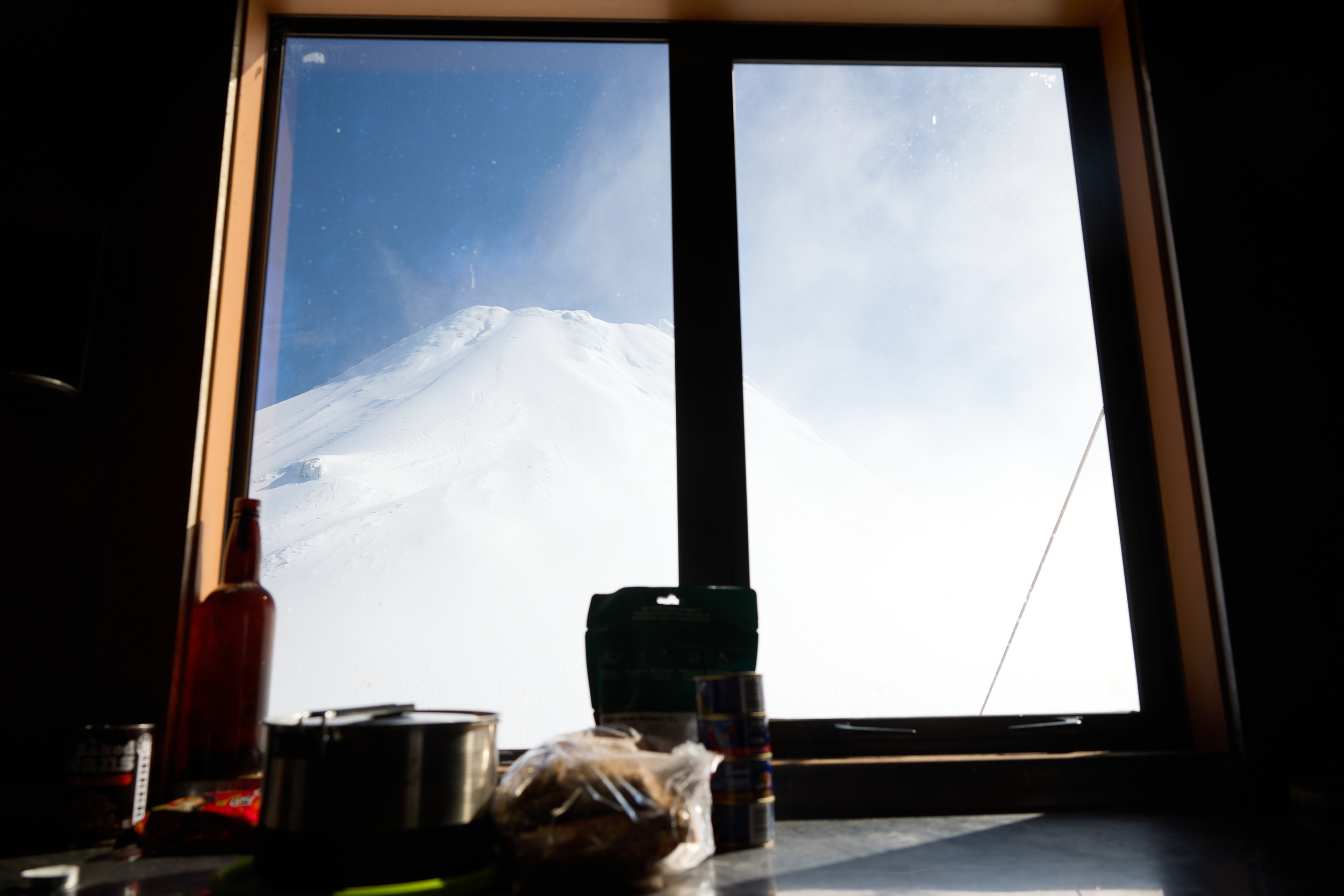 View of Taranaki Maunga out of Syme hut with food and cooking utensils in the foreground
